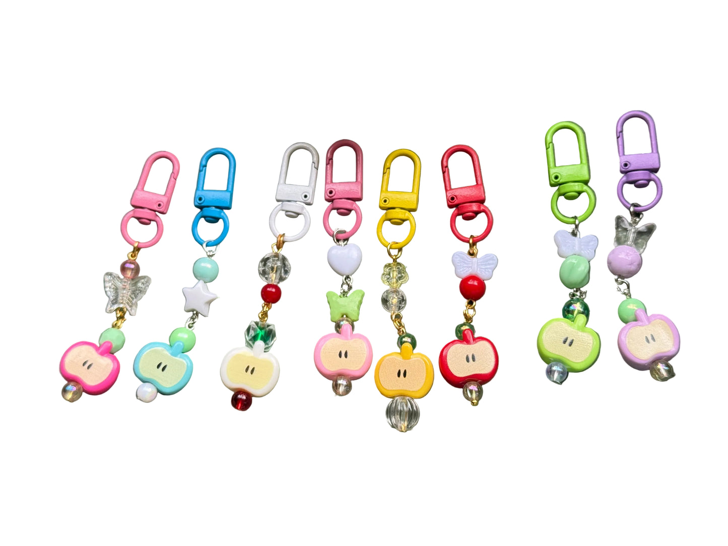 Colorful keychains with apple designs on a green surface